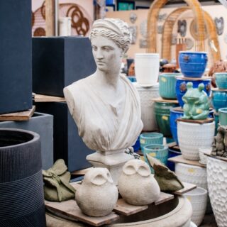 greco-style statue bust of a woman next to two small abstract owl statues