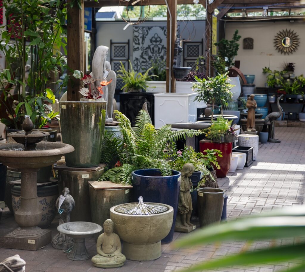 Assorted statues and fountains arranged by a lush fern