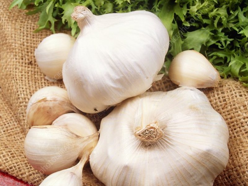 Several garlic bulbs arranged on burlap