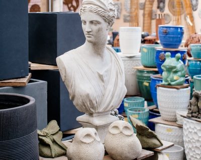 greco-style statue bust of a woman next to two small abstract owl statues